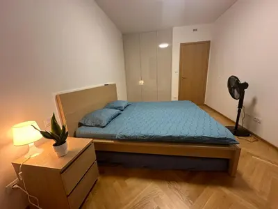 a bedroom with a bed with blue sheets and a fan at Smichov city Apartments in Prague