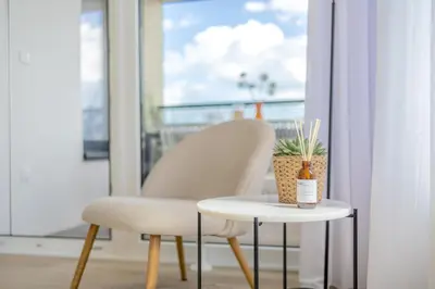 a chair and a table in front of a window at Bright 2BR - 8th floor, Balcony, Free Parking - by Gravity Prague in Prague