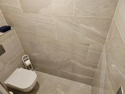 a bathroom with a toilet and a tiled wall at NEW Apartment - O2 Arena Prague with parking in Prague