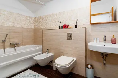 a bathroom with a toilet and a tub and a sink at Golden River Apartment in Prague
