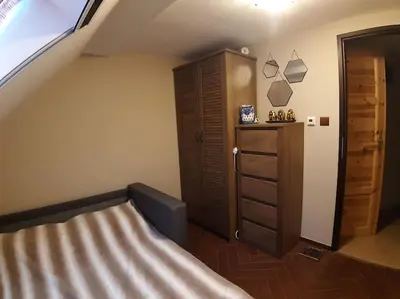 a bedroom with a bed and a wooden dresser at Лесной Коттедж Нова in Živohošť