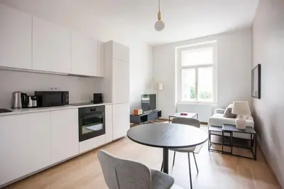 a white kitchen with a table and chairs in a room at Blueground - Vrsovice, furnished in Prague