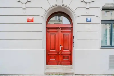 a red door in a white building with an archway at Blueground Žižkov renovated nr universities PRG-35 in Prague