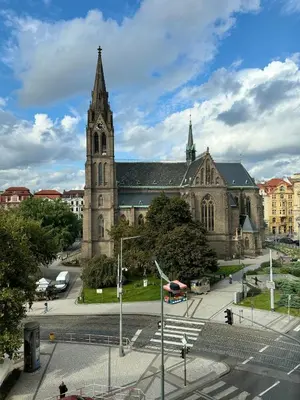 an old church with a clock tower in a city at Modern 2BED with st Ludmila view and entire square in Prague