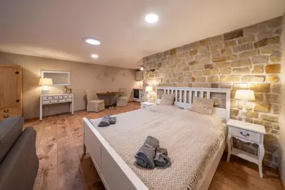 a bedroom with a large bed and a stone wall at Studio Flat - Sleeps 3 - Parking - Wifi in Hostivice