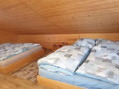 two beds in a room with a wooden ceiling at u dobroty in Nový Dŭm