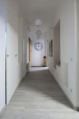 an empty hallway with white walls and a clock on the wall at Ocean Breeze Apartment in Prague