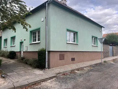 a green house with windows on the side of a street at Podkrovní apartmán se společným bazénem in Zlonice