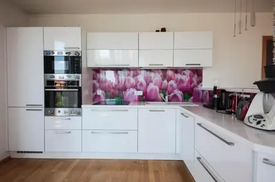 a white kitchen with pink flowers on the wall at Prostorný byt 3kk s krásnou terasou a vnitřním parkem in Prague