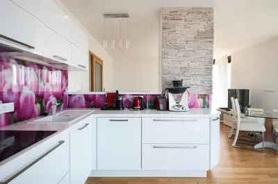 a kitchen with white cabinets and pink wallpaper at Cosy and spacious apartment with the view to the garden in Prague