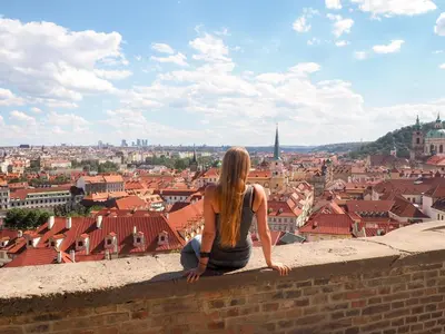 a woman sitting on a wall looking at a city at Soukromý pokoj B4 káva v ceně in Prague