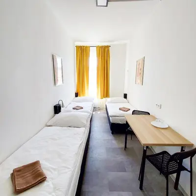 a room with two beds and a wooden table at Sunny room in centre of Prague H1 in Prague