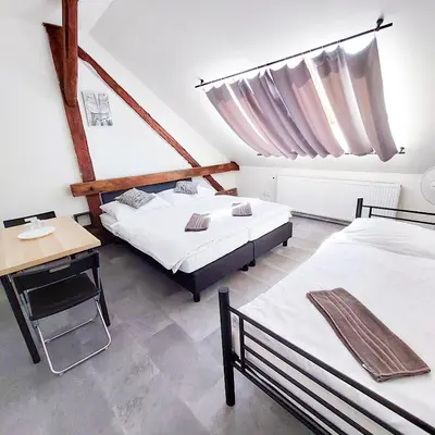 a bedroom with two beds and a table and a desk at Útulný podkrovní pokoj R4 v Praze in Prague