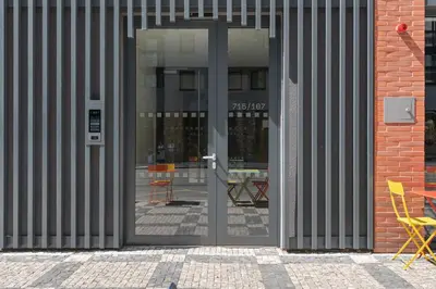 an open glass door of a building with chairs inside at REAL Living by REFA Karlin 408 in Prague