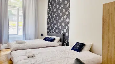 a bedroom with two beds and a wall with a window at Prague service Apartment - Central square location in Prague
