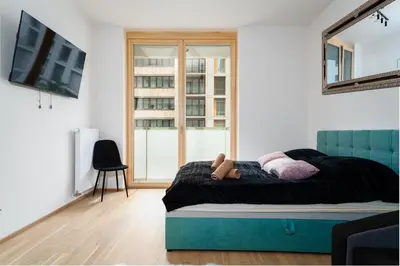 a bedroom with a bed with a blue headboard and a window at Modern Deluxe Suite in Prague