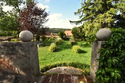 a garden with a stone fence in the grass at Suite at Château Domoušice in Domoušíce