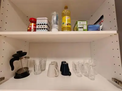 a kitchen shelf with glasses and utensils at Comfy place in Prague