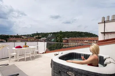 a woman sitting in a hot tub on a balcony at Royal Skyline Penthouse in Prague