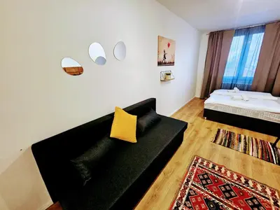 a living room with a black couch with a yellow pillow at SUPERIOR PRAGUE 2BR APARTMENT for Business & Leisure, Private Garden, Free Parking & Gym, by LIVE-INN 1 in Prague