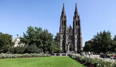 a church with a tall tower and a grass field at Sibelius Apartments Prague - Art Nouveau Residence 1902 in Prague
