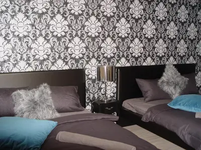 a bedroom with two beds and a damask wallpaper at Riverside SPIRIT in Prague