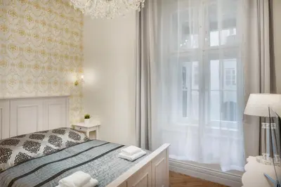a white bedroom with a bed and a window at Mikulášská - Old Town Square View Residence in Prague