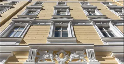 a yellow building with windows and statues on it at Angelo Roma in Prague