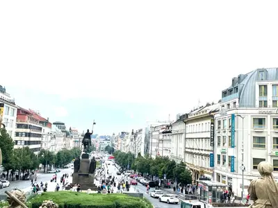 a busy city street with a statue in the middle at Prague National Museum Apartment in Prague
